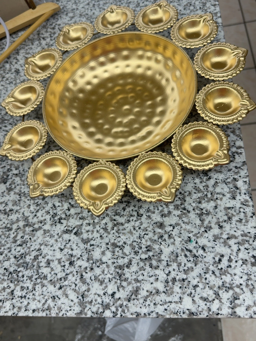 Brass urli bowl surrounded by diya holders